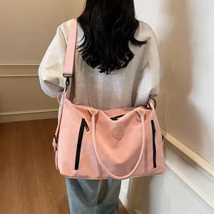 Pink large travel bag on shoulder showing the adjustable strap and logo detail