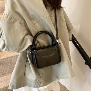 Mannequin portant un sac à main noir brillant avec poignée ronde épaisse et bandoulière