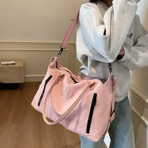 Pink travel bag detail featuring front circular logo and high-quality hardware zippers