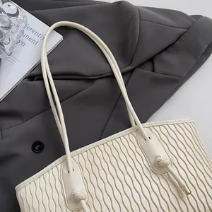 Detail of off-white tote bag showing elegant 3D wavy texture and slender shoulder straps