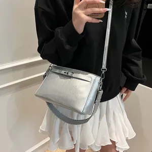 Close-up of metallic silver bag featuring woven handle and polished metal lock
