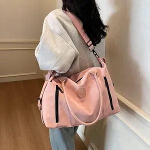 Detailed side view of large pink travel bag with embossed logo and wide shoulder strap