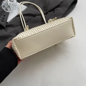 Detail shot of cream shoulder bag featuring vertical pleated leather and gold hardware