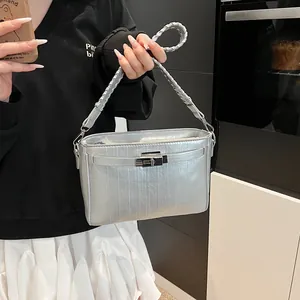 Detail of silver metallic textured leather bag with signature turn-lock and woven handle