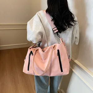 Close-up of pink frosted travel tote bag featuring front zipper pockets and leather logo