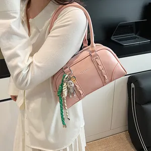 Close-up of pink Boston bag featuring woven leather side and a decorative bear charm