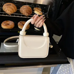Détail d'un mini sac carré blanc crème avec poignée à billes et bandoulière amovible