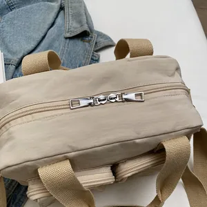 Detail view of khaki nylon handbag featuring double-way metal zippers and side pockets