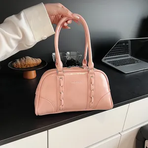 Detailed shot of pink glossy PU leather Boston bag with metallic eyelet woven straps