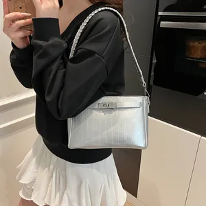 Detail of silver metallic shoulder bag showing rectangular twist lock and woven strap texture