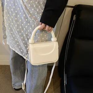 Gros plan d'un mini sac blanc avec poignée sphérique et fine bandoulière réglable