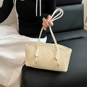 Detailed close-up of cream pleated texture and decorative knot detail on the shoulder bag