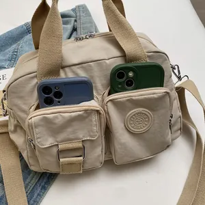Detail view of beige nylon commuter bag showing double front pockets with phone storage