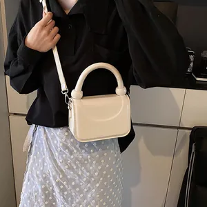 Détail du mini sac carré en cuir verni crème avec boucles argentées et anse ronde