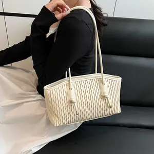 Detail of creamy white tote bag with vertical pleated texture and knotted strap detail