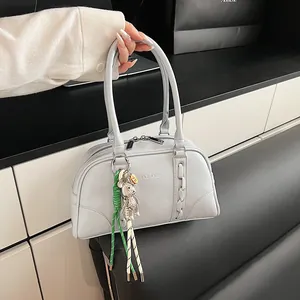 Detail of grey PU leather Boston bag featuring woven side trim and a bear charm