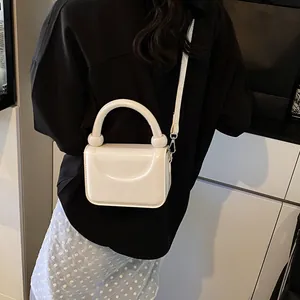 Vue détaillée d'un sac bandoulière blanc avec poignée à décor sphérique de dos