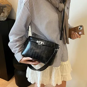 Detail of black textured patent leather bag with silver lock and woven strap