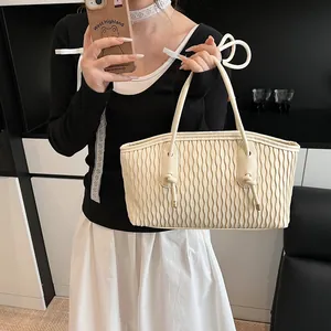 Detailed view of cream ruffled texture handbag with long handles and drawstring bow