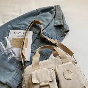 Detail view of beige nylon commuter bag with multiple pockets and fashion logo label