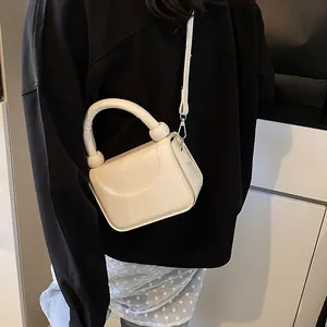 Détail du petit sac bandoulière blanc crème avec poignée en arc et détails argentés