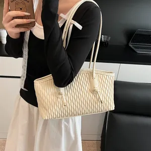 Macro detail of off-white tote bag featuring vertical pleated texture and knotted strap