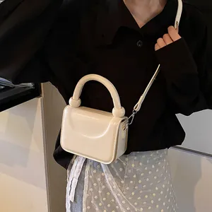 Vue détaillée du mini sac carré crème au fini brillant avec des perles sur la poignée