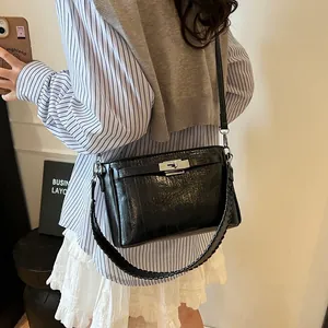 Detail of black glossy embossed leather bag with silver buckle and braided strap