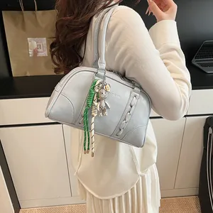 Detail of light blue Boston bag featuring a metal bear charm and colorful rope accents