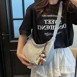 Λεπτομέρεια ασημένιας τσάντας μισοφέγγαρο με αλυσίδα πέρλας και κρεμαστό αρκουδάκι