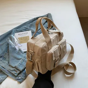Detail of a beige nylon crossbody bag with multiple pockets and wide shoulder straps