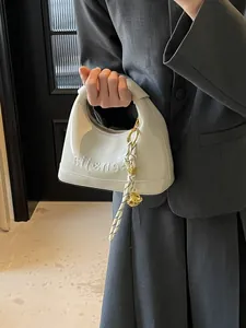 White glossy faux leather hobo bag with embossed lettering and woven tassel detail
