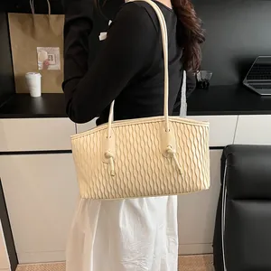 Detailed view of beige pleated tote bag featuring decorative knot and gold hardware finish