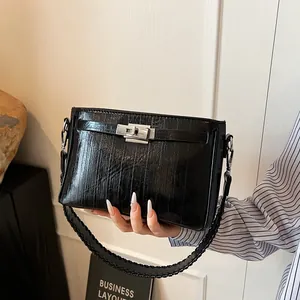 Detailed close-up of glossy black leather handbag with silver twist lock and woven strap