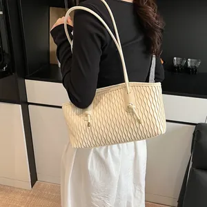 Detail of cream large tote bag with wave textured surface and metallic knot accents