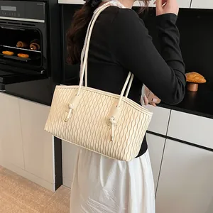 Close-up of off-white tote bag with wave embossed texture and elegant knot charms