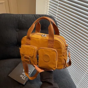 Detail of caramel nylon crossbody bag featuring double handles and front zipper pockets