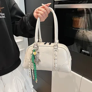 Close-up of beige shoulder bag showing woven stitching detail and bear charm accessory