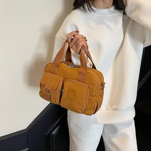 Detail of ginger yellow nylon crossbody bag featuring multi-pocket design and fashion logo