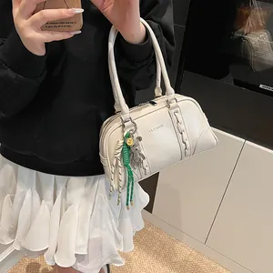 Elegant cream-colored Boston handbag with decorative charms shown in a lifestyle mirror selfie