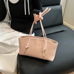 Detail of pink shoulder bag with vertical pleated texture and knotted strap design