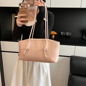 Detail of light pink tote bag featuring vertical pleated texture and knotted shoulder straps