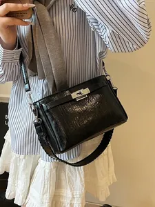 Glossy black patent leather Kelly bag with silver twist lock and woven shoulder strap