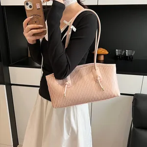 Detail of light pink tote bag featuring vertical wave pattern and knotted shoulder strap