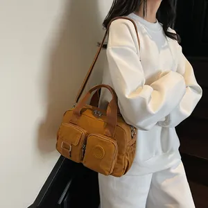 Detail of a ginger yellow nylon multi-pocket crossbody bag with adjustable strap