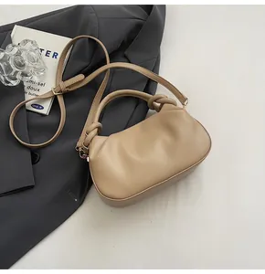 Detailed close-up of khaki pleated PU leather handbag with knot handle and gold hardware