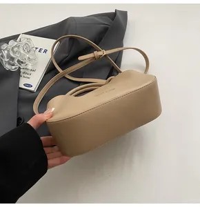 Top view of beige leather pleated handbag with shoulder strap on a grey suit and book
