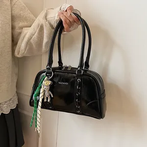 Detail of glossy black leather bowling bag with rhinestone bear charm and woven rope décor