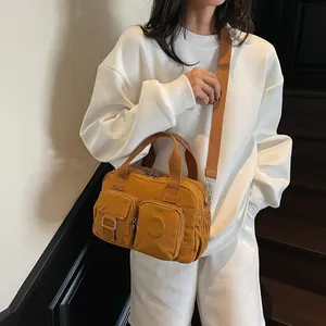 Detail of mustard yellow nylon crossbody bag with dual handles and utility zipper pockets