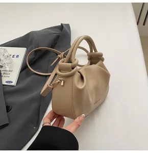 Close-up of beige pleated cloud handbag showing side logo and adjustable shoulder strap